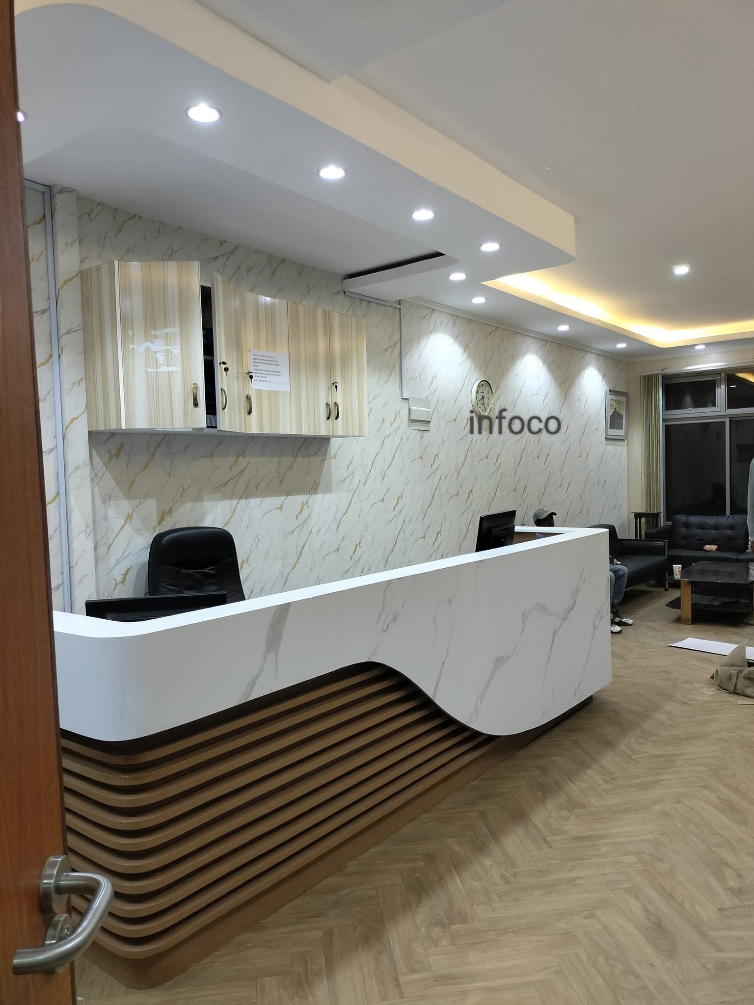 Curved marble reception desk with gold trim in Infoco office