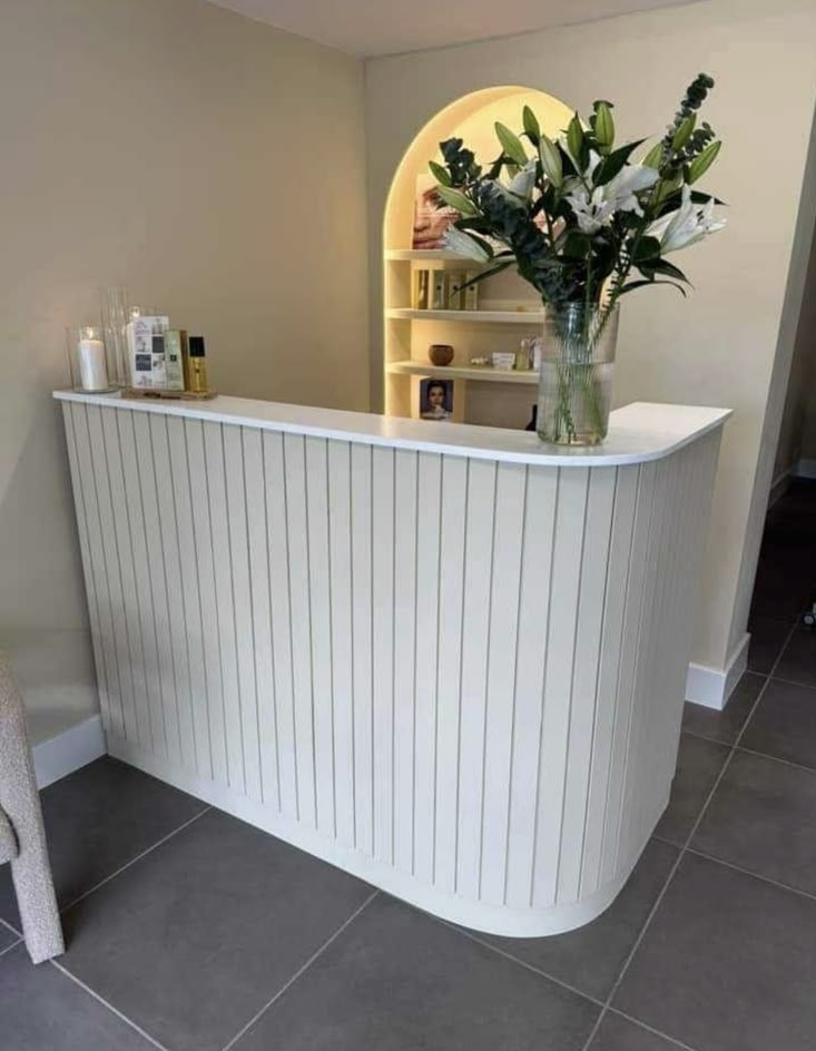 White fluted reception desk styled with fresh flowers