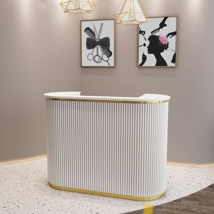 White and gold fluted salon reception desk with framed wall art