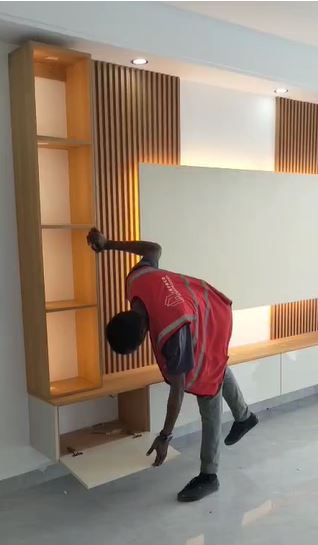Team member installing timber slat feature wall with backlighting